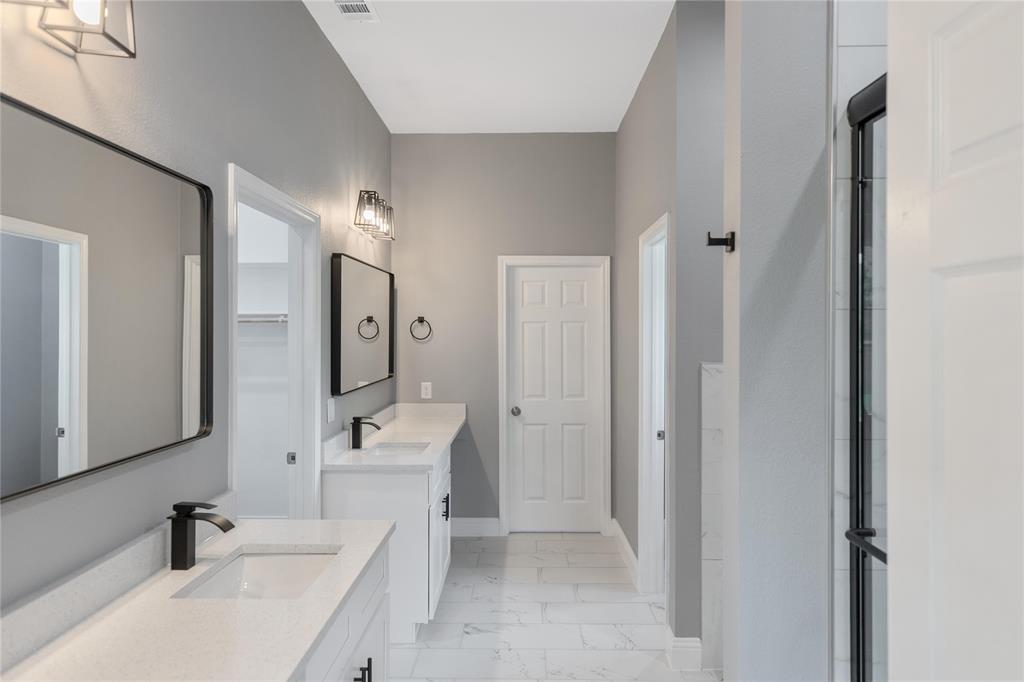Full bathroom featuring two vanities and light marble finish flooring