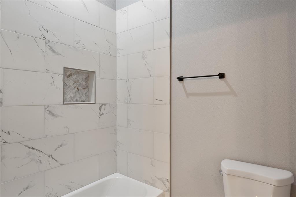 Full bath with shower / bathtub combination and a textured wall