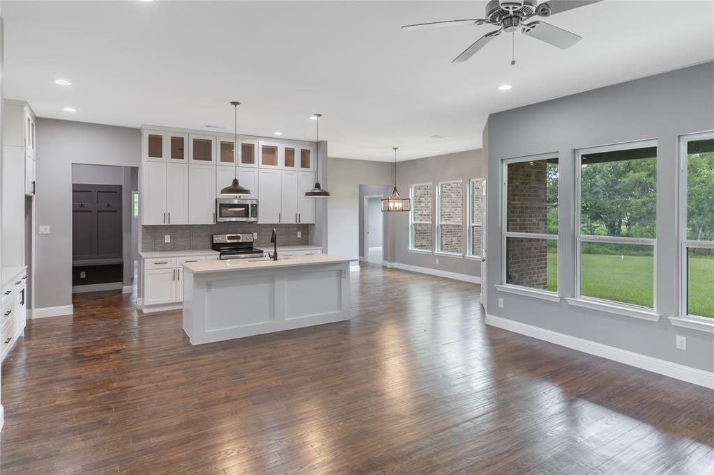 Kitchen featuring glass insert cabinets, tasteful backsplash, decorative light fixtures, white cabinets, and appliances with stainless steel finishes