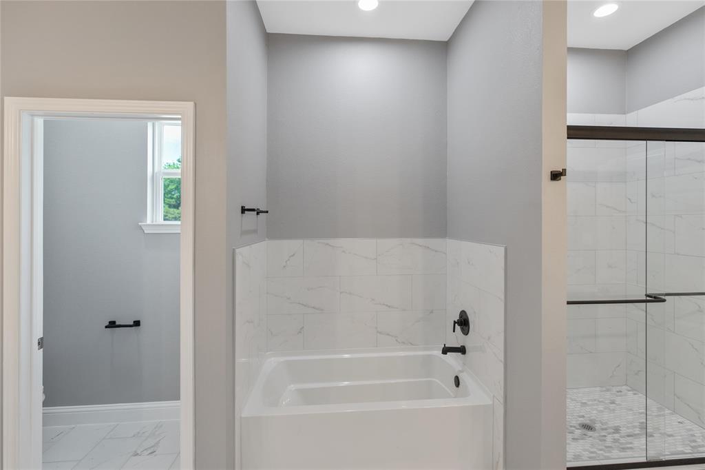 Full bathroom with a garden tub, marble finish floors, and a stall shower
