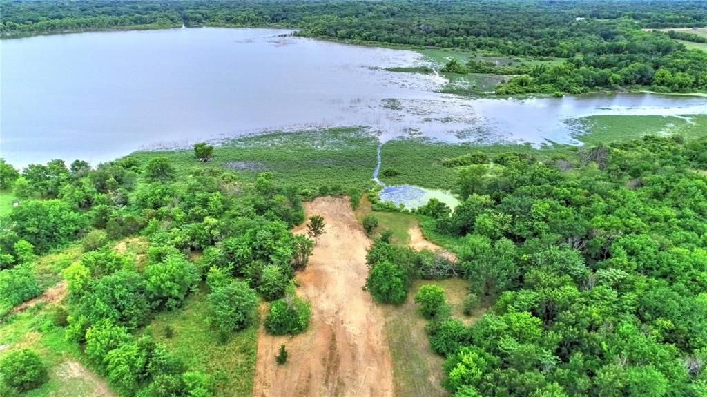 Aerial view of property and surrounding area featuring a heavily wooded area and a large body of water