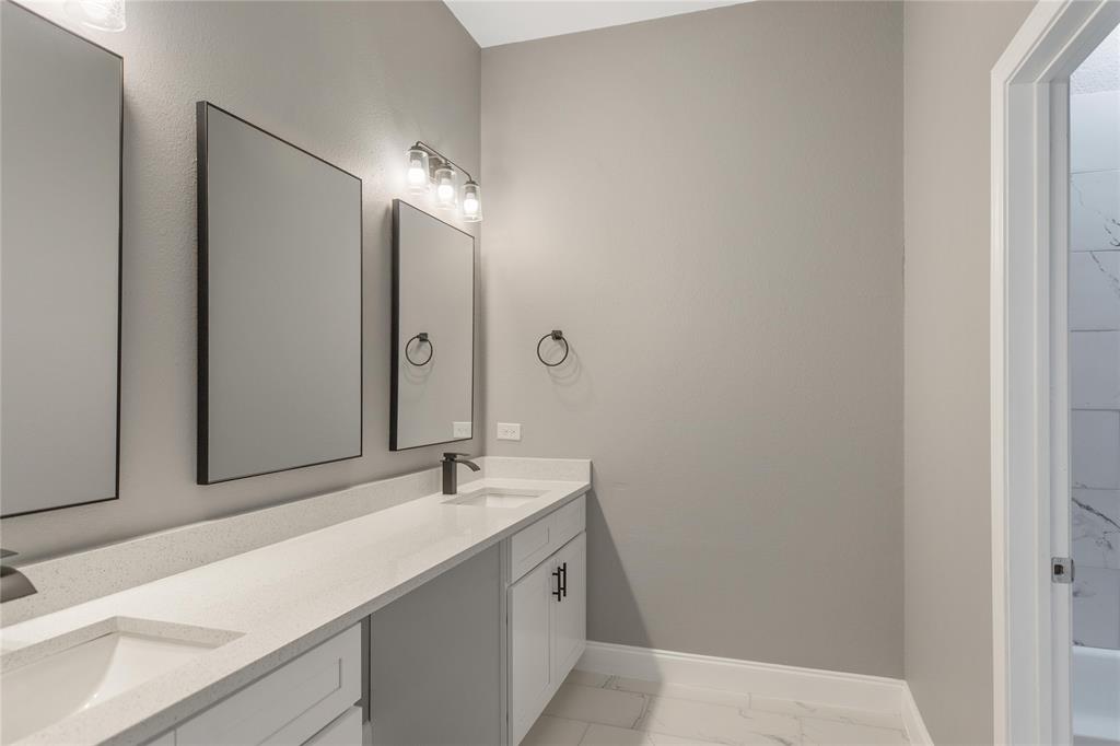 Bathroom with double vanity and light marble finish floors