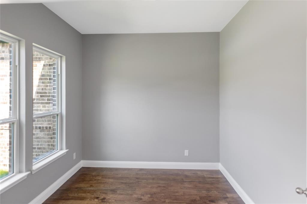Empty room featuring baseboards and dark wood-type flooring