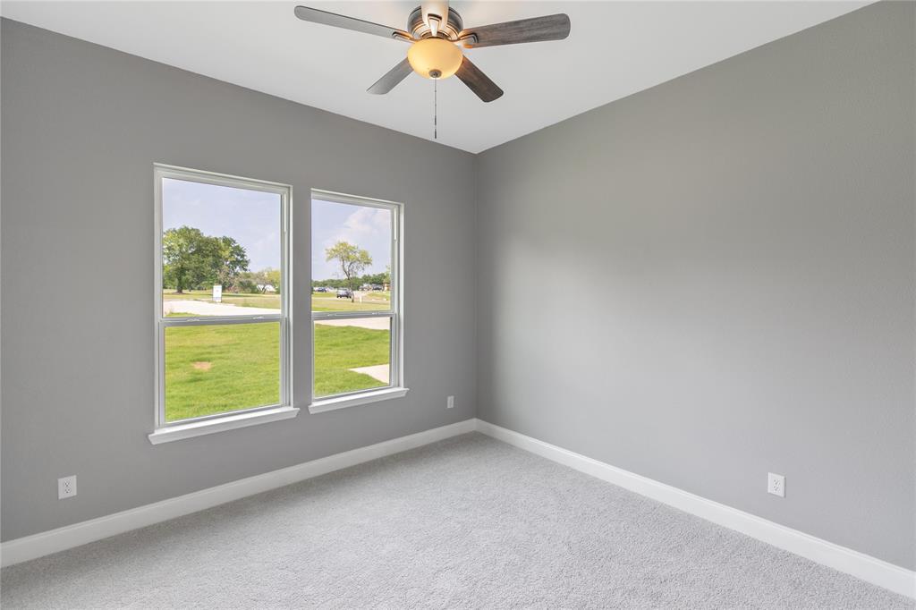 Carpeted empty room with baseboards and a ceiling fan