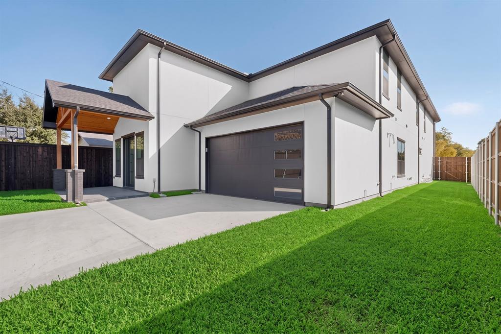 Modern exterior featuring smooth-finish siding, a multi-car garage with horizontal glass paneling, and a covered patio with wood-paneled ceiling