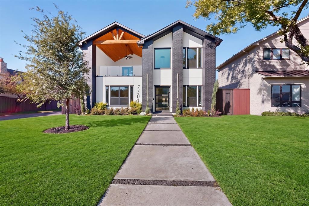 Two-story contemporary exterior featuring dark brick accents, high-contrast white siding, a covered upper-level balcony with wood-toned ceiling finishes, and a linear paver walkway Two-story contemporary exterior featuring dark brick accents, high-contrast white siding, a covered upper-level balcony with wood-toned ceiling finishes, and a linear paver walkway