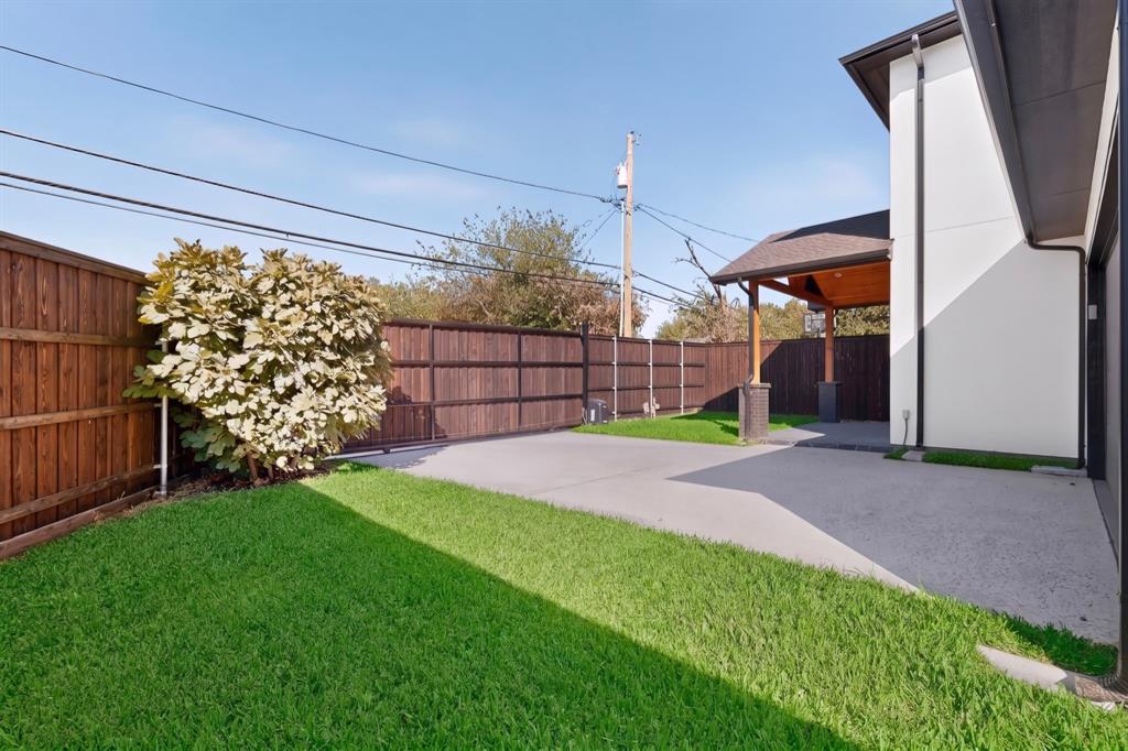 Fenced backyard featuring a manicured lawn, concrete patio, and a covered porch with wood-finish ceiling detailing