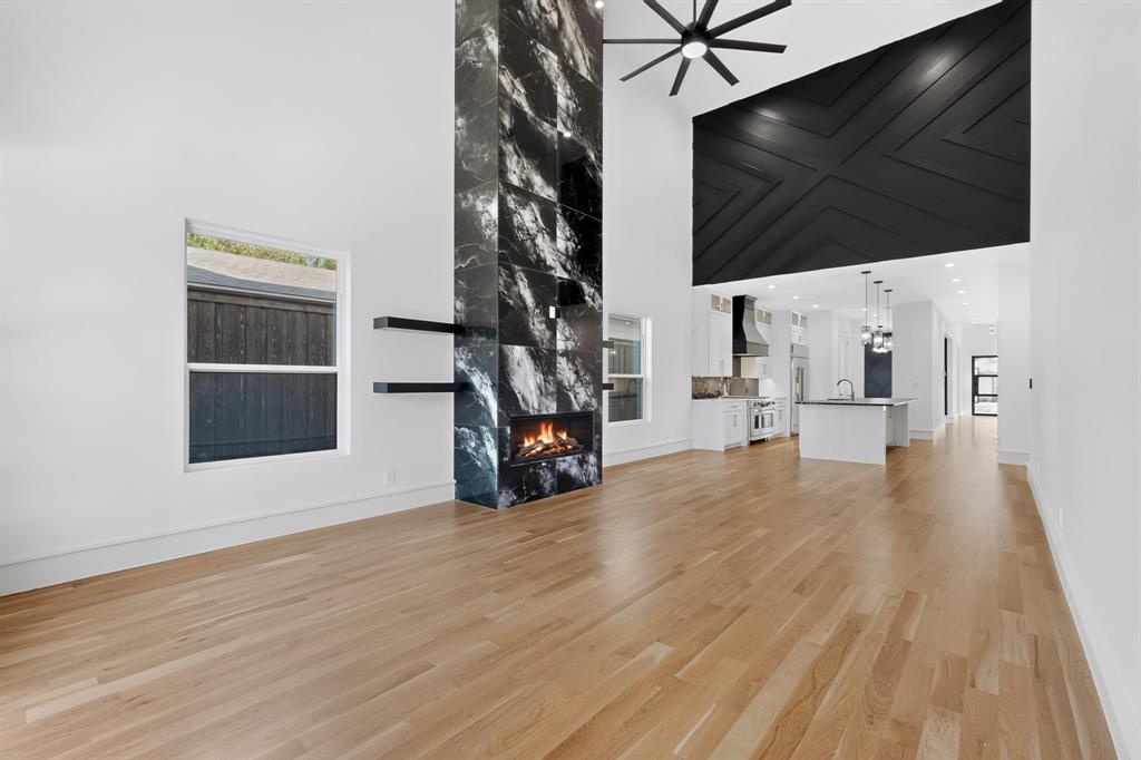 Double-height ceiling, floor-to-ceiling stone-clad fireplace, black geometric wall detailing, hardwood flooring, and large-format windows Double-height ceiling, floor-to-ceiling stone-clad fireplace, black geometric wall detailing, hardwood flooring, and large-format windows