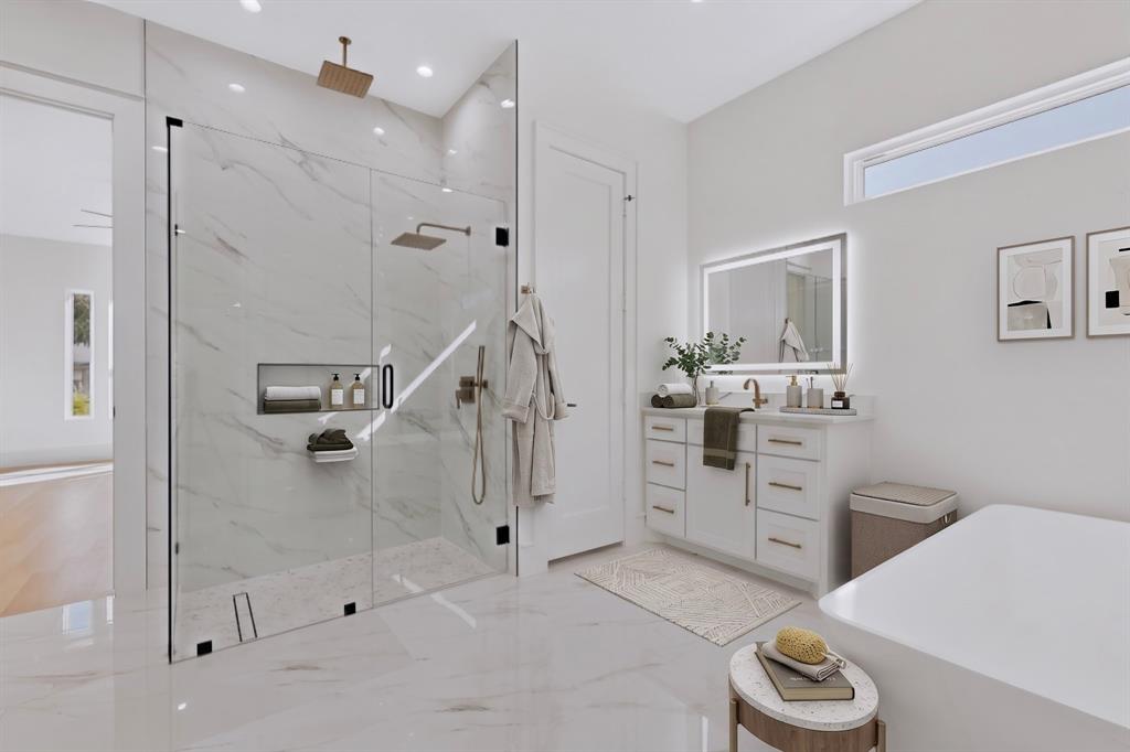 Walk-in glass-enclosed shower with a recessed niche and rain-style showerhead, vanity with dual-toned hardware and a back-lit mirror, and a soaking tub