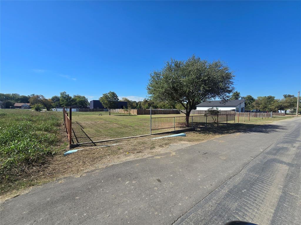 Cleared lot featuring a level grass landscape, perimeter metal fencing, and mature trees Cleared lot featuring a level grass landscape, perimeter metal fencing, and mature trees