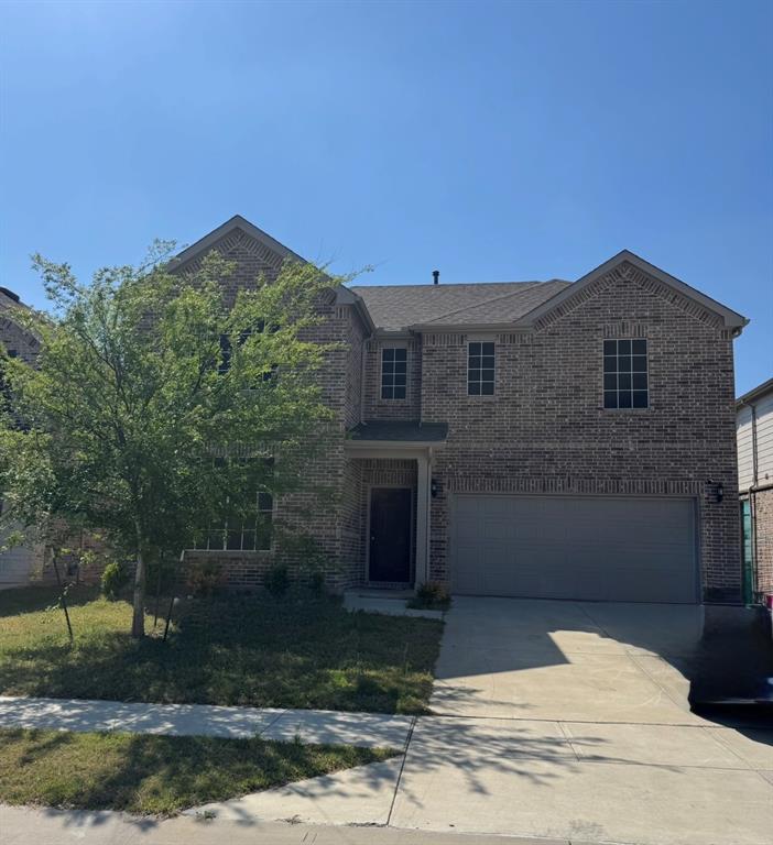 Home two-story brick exterior featuring a covered entry, multiple windows with grids, an attached two-car garage, and a concrete driveway