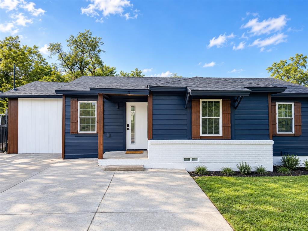 Exterior featuring dark lap siding, white brick masonry, wood-finish shutters, and an integrated single-car garage