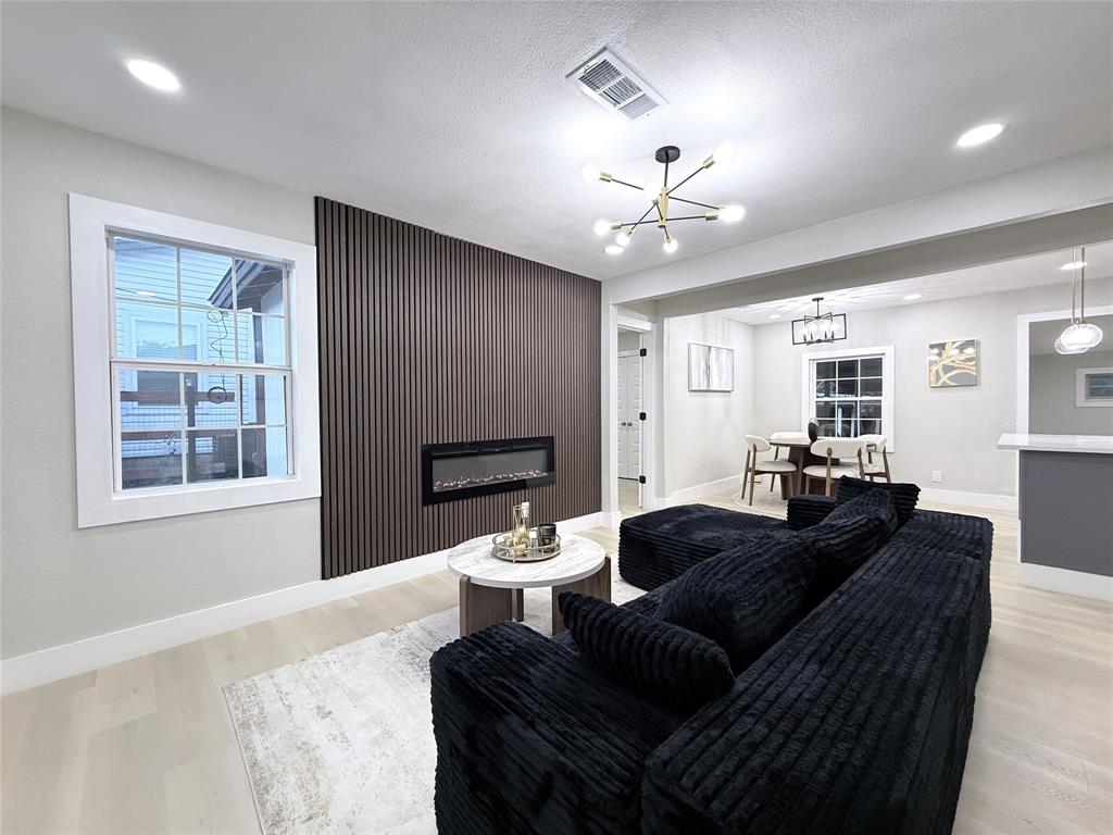 Vertical wood-slat accent wall featuring a recessed electric fireplace, multi-arm modern light fixture, and wood-finish flooring
