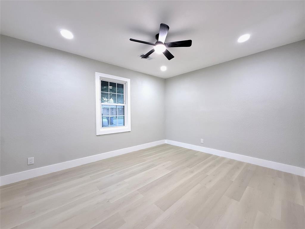 Neutral-toned interior featuring wood-finish flooring, recessed lighting, a ceiling fan with an integrated light fixture, and a single-hung window with a classic frame