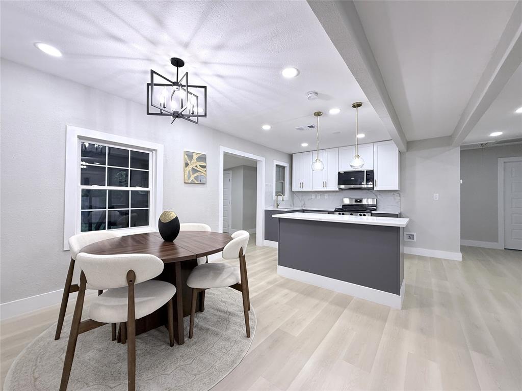Kitchen featuring white upper cabinetry, dark base cabinetry, a breakfast bar, recessed lighting, and wood-finish flooring