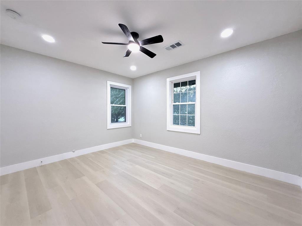 Neutral wall tones, wood-finish flooring, recessed lighting, and a multi-blade ceiling fan with integrated lighting