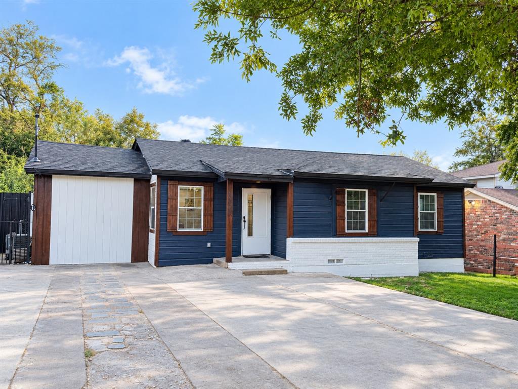 Single-story exterior featuring navy horizontal siding, contrasting white brick accents, dark-stained wood shutters, a covered front entry, and an attached garage