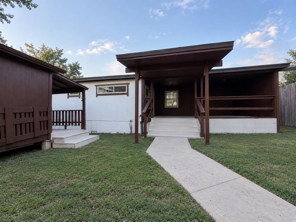 Exterior featuring two covered wooden decks with railings, a paved concrete walkway, and white siding