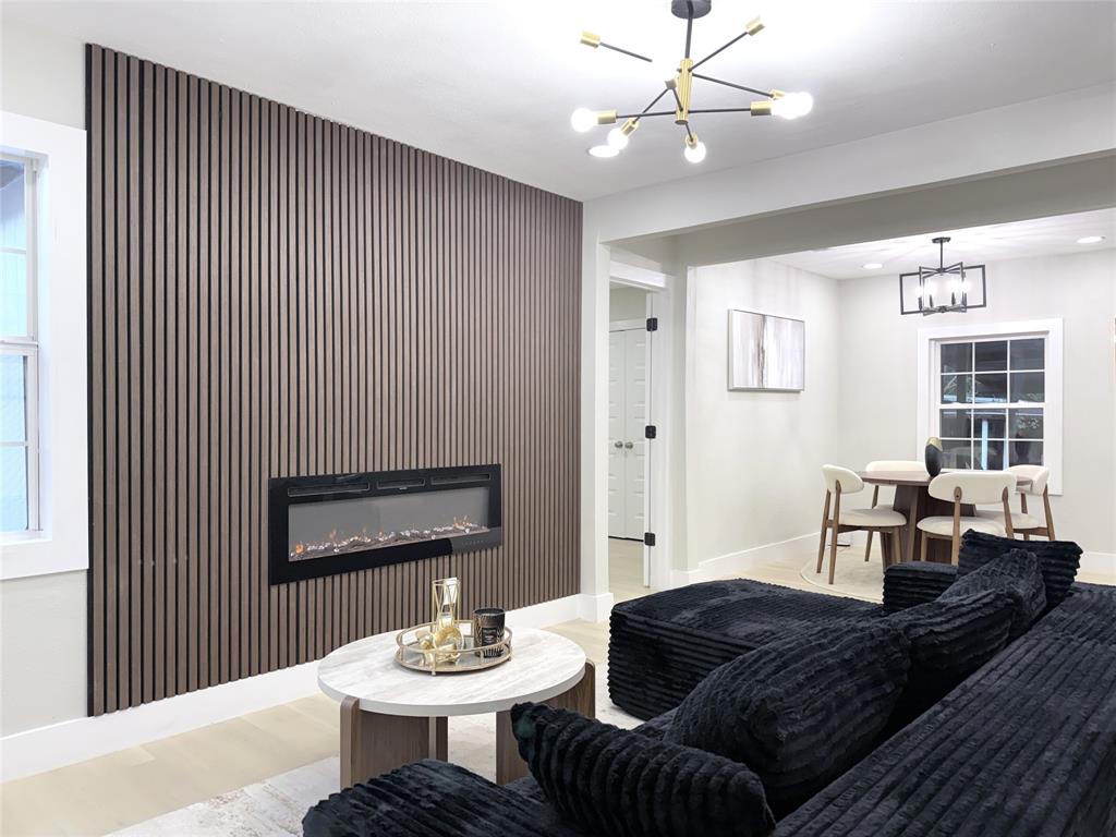 Floor-to-ceiling slatted wood-finish wall accent, integrated linear electric fireplace, modern multi-arm sputnik chandelier, and recessed lighting