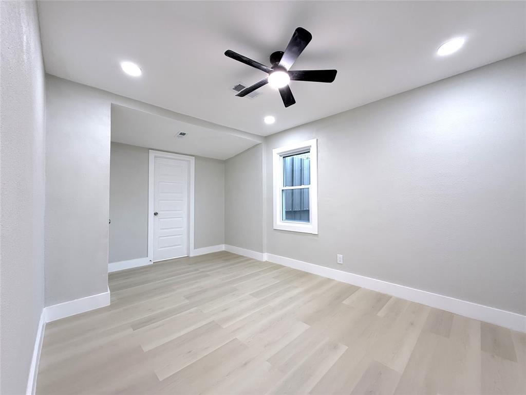 Neutral interior space featuring wood-finish flooring, recessed lighting, a ceiling fan with integrated light, and a white five-panel interior door