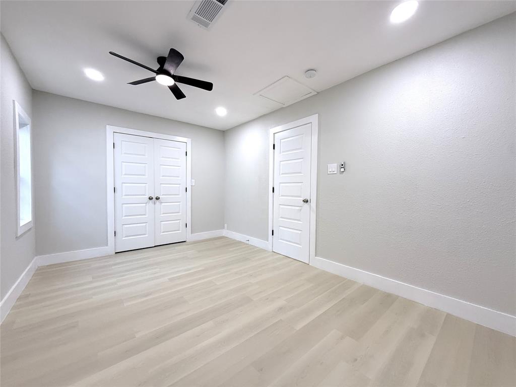 Neutral-toned interior featuring wood-finish flooring, recessed lighting, matte black ceiling fan, and multi-panel doors