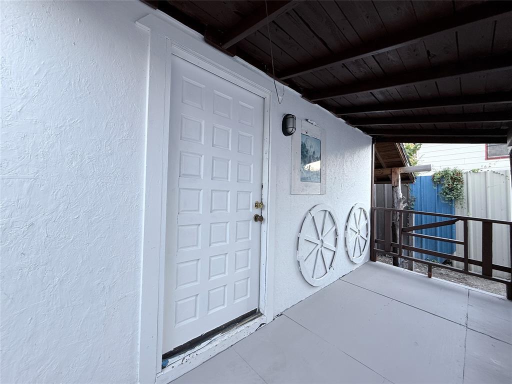 Covered porch featuring a textured stucco exterior, wood-plank ceiling, solid-panel entry door, and perimeter railing