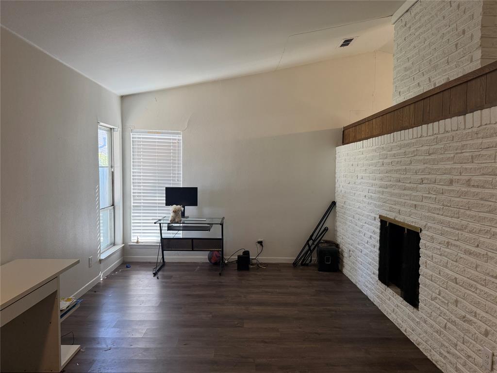 Vaulted ceilings, wood-finish flooring, and white-painted brick fireplace with a wood-trim mantle
