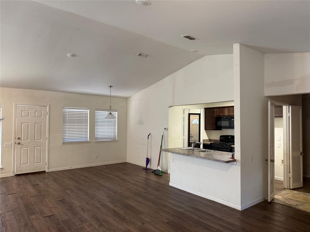 Vaulted ceilings, wood-finish flooring, breakfast bar with stone-finish countertop, dual-window configuration, and paneled entry door