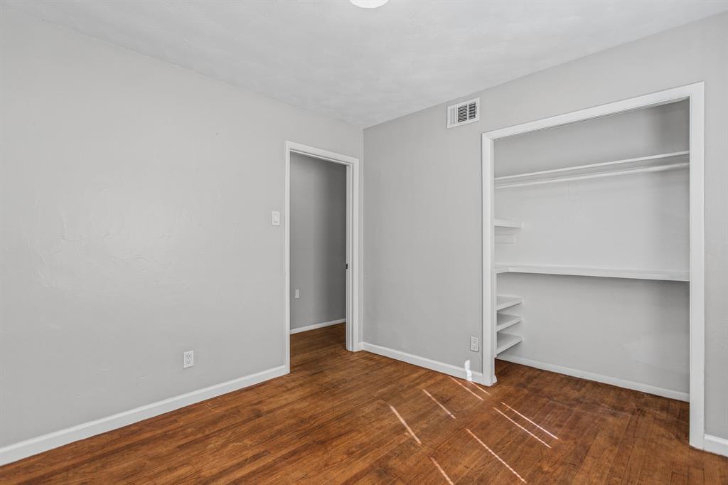 Room featuring wood-finish flooring, neutral wall paint, and a built-in closet with integrated shelving
