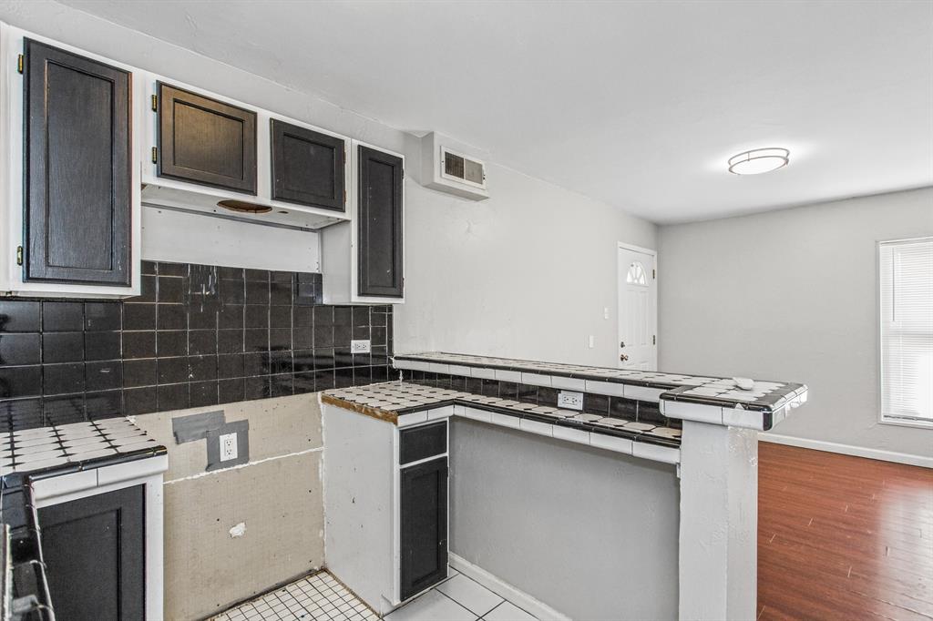 Kitchen featuring dark-toned cabinetry, tiled backsplash, built-in breakfast bar with tiled surface, and wood-finish flooring