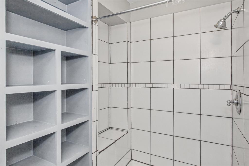 Built-in floor-to-ceiling shelving, tiled walk-in shower with integrated bench seat, and chrome plumbing fixtures