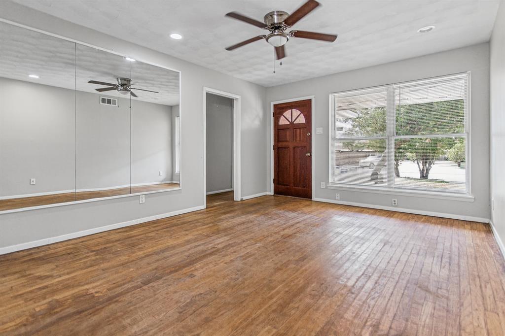 Wood-finish flooring, large wall-mounted mirrors, recessed lighting, ceiling fan with light fixture, and solid wood exterior door with arched glass panel Wood-finish flooring, large wall-mounted mirrors, recessed lighting, ceiling fan with light fixture, and solid wood exterior door with arched glass panel