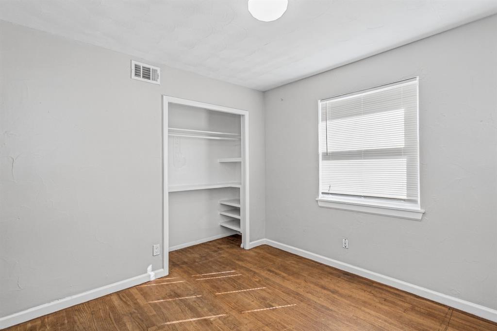 Room featuring wood-finish flooring, neutral wall paint, and a recessed closet with built-in shelving