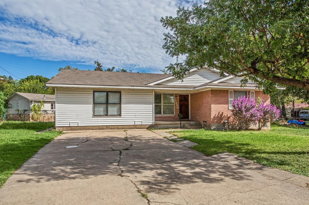 Single-story exterior featuring a brick and horizontal siding facade, asphalt shingle roof, concrete driveway, and mature landscaping