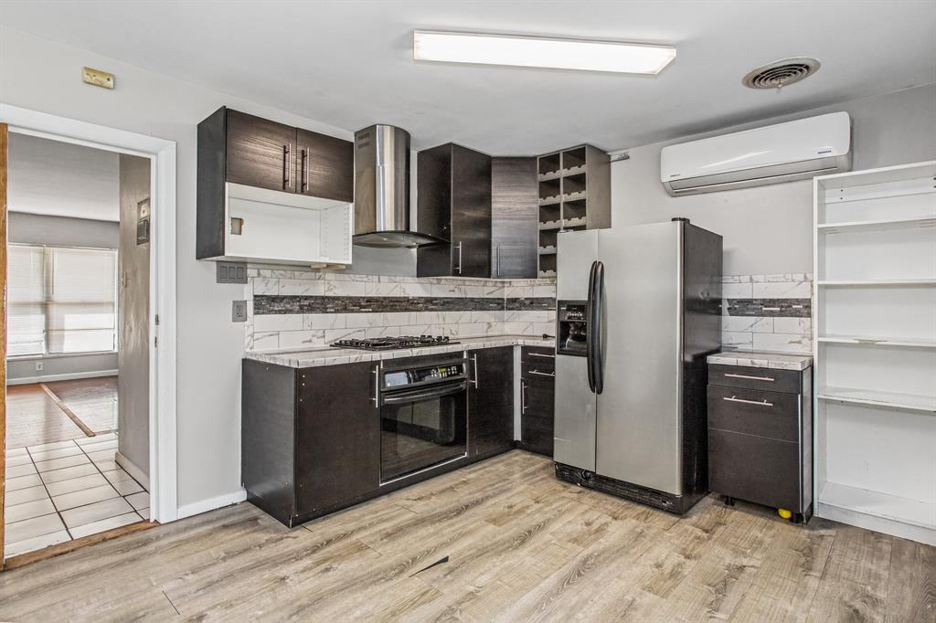 Kitchen featuring dark wood-finish cabinetry, stainless steel appliances, a tile backsplash, wood-finish flooring, and a built-in wine rack