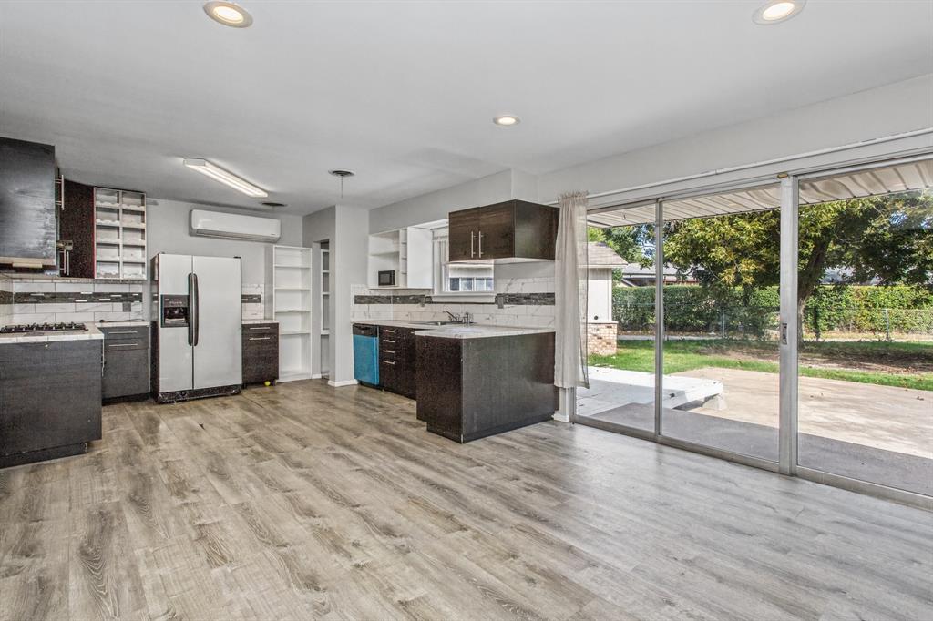 Kitchen featuring dark cabinetry, stone-finish countertops, wood-finish flooring, recessed lighting, and sliding glass doors to the exterior