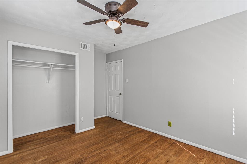 Room featuring wood-finish flooring, a ceiling fan with integrated lighting, and a closet with a built-in shelf and rod