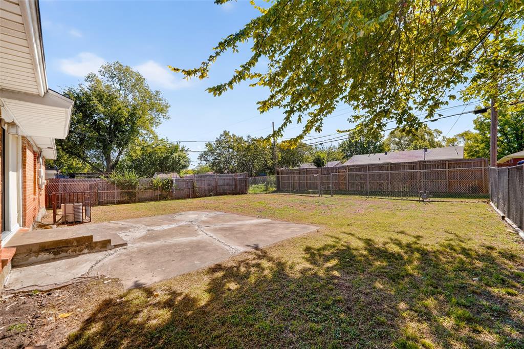 Rear yard featuring a concrete patio, open lawn area, and perimeter wood fencing