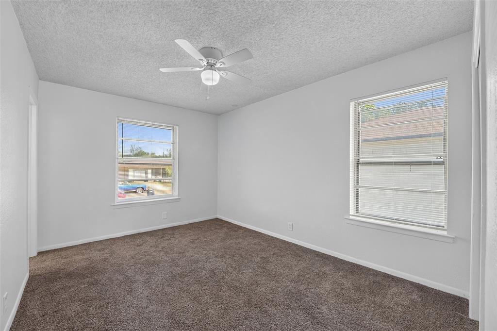 Room interior featuring wall-to-wall carpeting, two dual-pane windows with horizontal blinds, and a central ceiling fan with integrated lighting