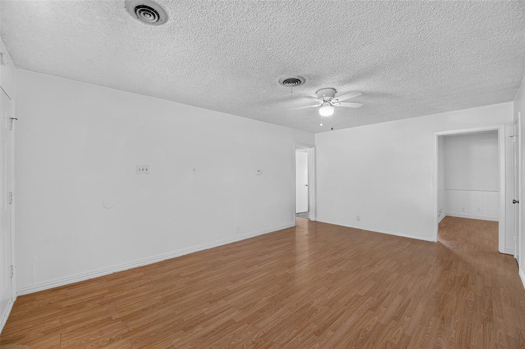 Interior space featuring wood-finish flooring, white walls, and a ceiling-mounted light fixture with fan Interior space featuring wood-finish flooring, white walls, and a ceiling-mounted light fixture with fan