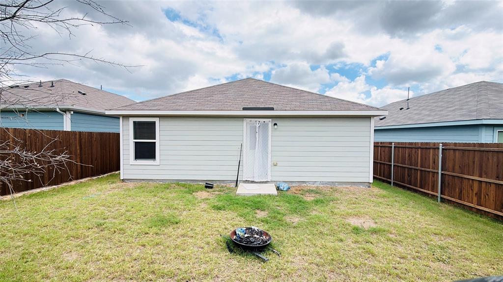 Rear exterior featuring horizontal lap siding, a hipped roof, and a fully fenced backyard