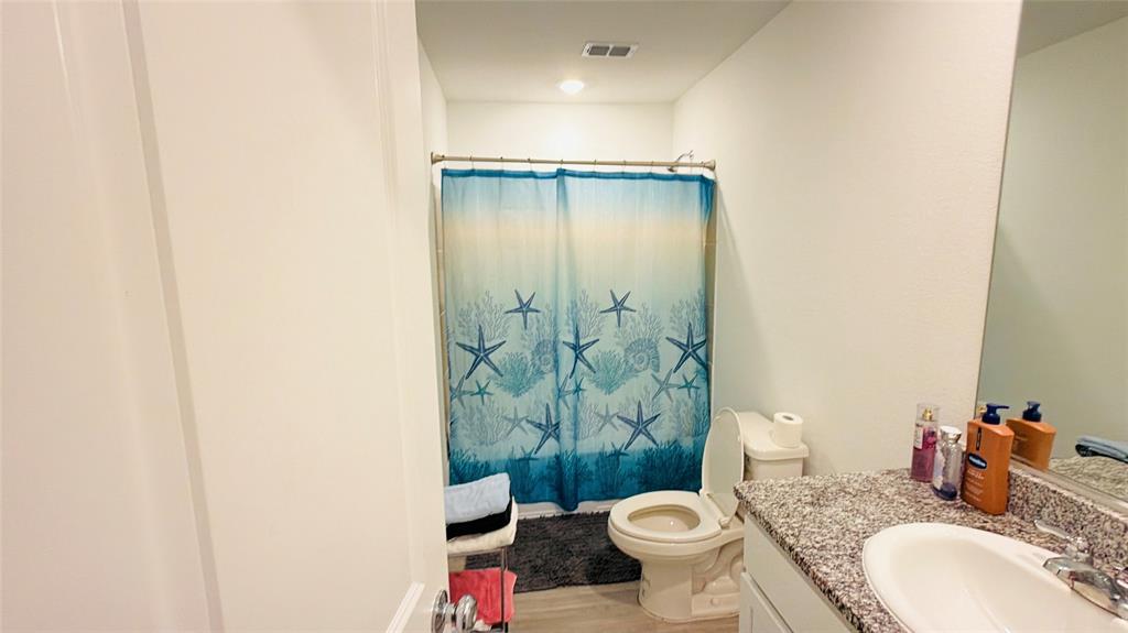 Bathroom featuring a stone-composite countertop, integrated oval sink, chrome faucet, wall-to-wall vanity mirror, and a tub-shower combination with a curved shower rod