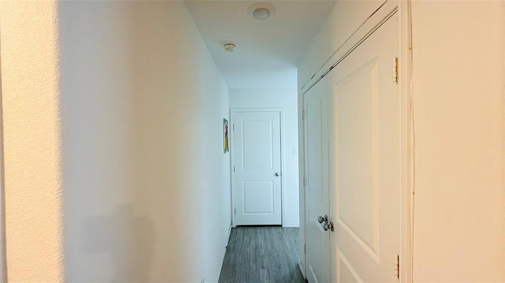 Hallway featuring wood-finish flooring, two-panel interior doors, and recessed ceiling lighting