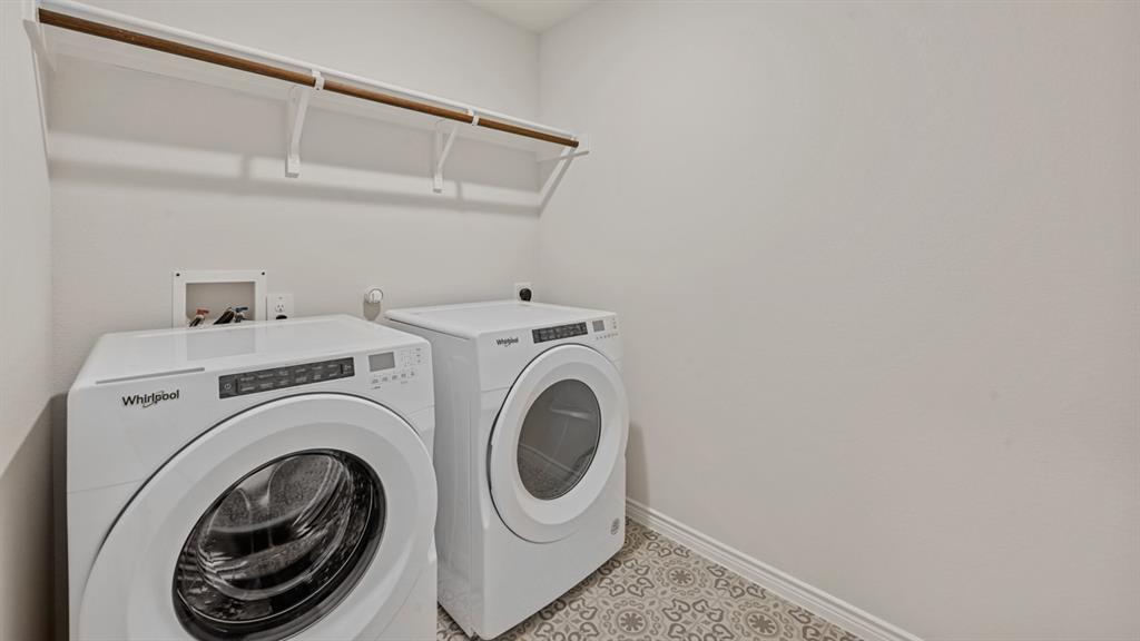 Dedicated laundry area with patterned floor tiles, overhead shelving, and a garment rod