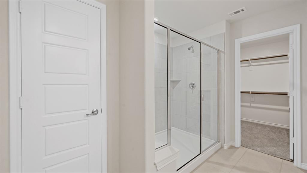 Shower with a glass enclosure, tiled walls, and a built-in shelf