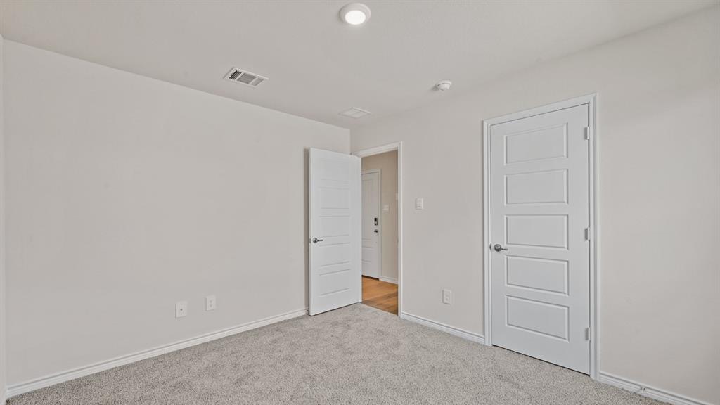 Light gray wall color, textured carpeting, recessed lighting, and a paneled interior door
