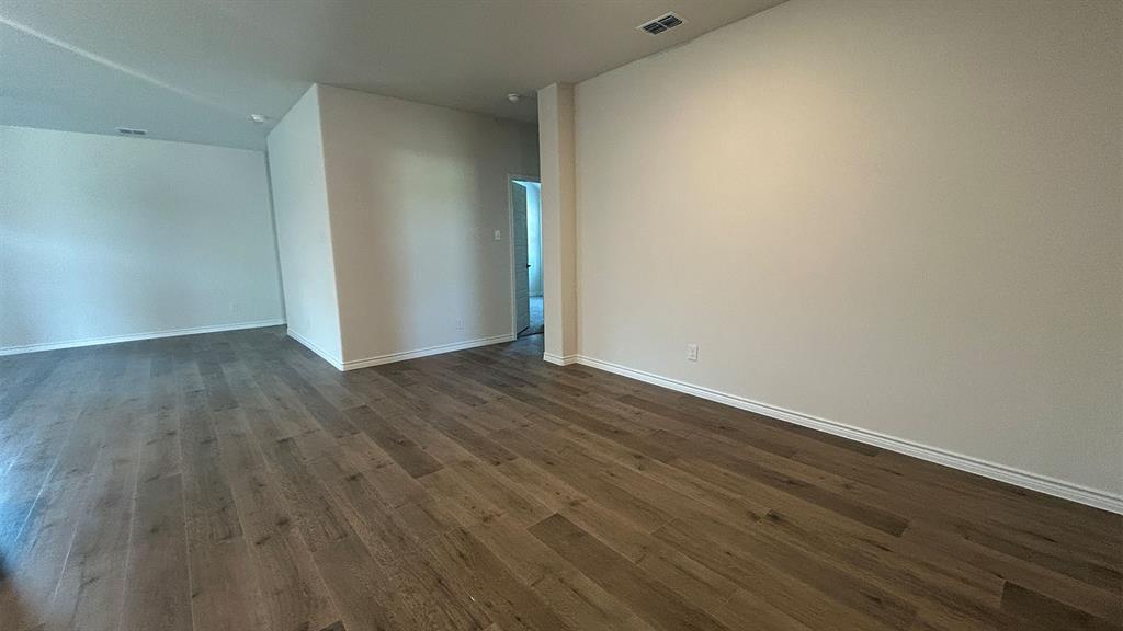 Neutral-toned interior space featuring wood-finish flooring and smooth, high-reaching ceilings
