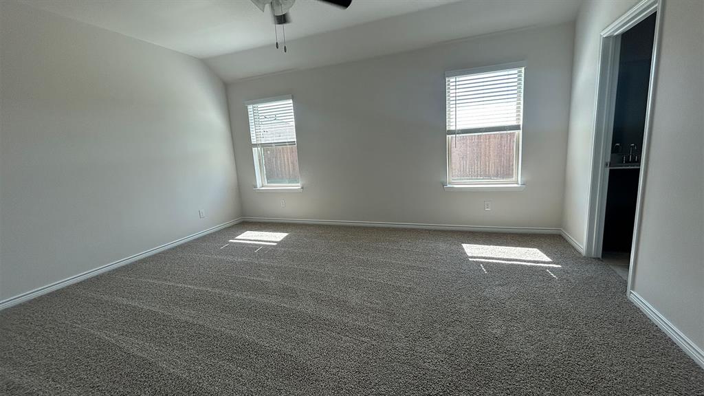 Bedroom featuring neutral wall-to-wall carpeting, vaulted ceilings, a ceiling fan, and two windows with horizontal blinds