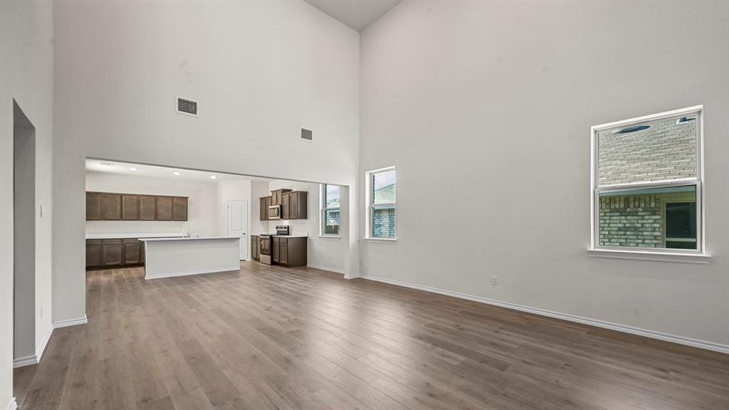 Vaulted ceilings, wood-finish flooring, two windows, recessed lighting, and a kitchen featuring dark wood cabinetry and white countertops