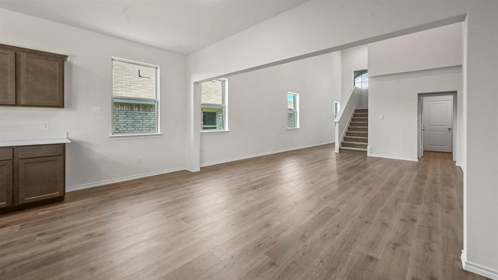 Spacious open-concept interior with wood-finish flooring, white walls, and abundant natural light from multiple windows